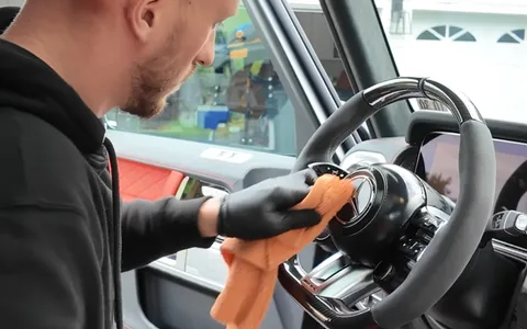 A gloved hand wiping down the steering wheel of a G63