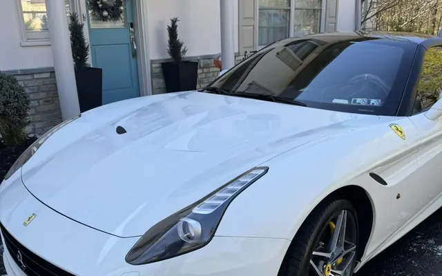 A clean white Ferrari California on a residential driveway